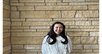 a person smiling in front of a brick wall