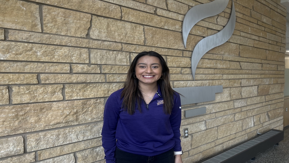 a person smiling in front of a stone wall