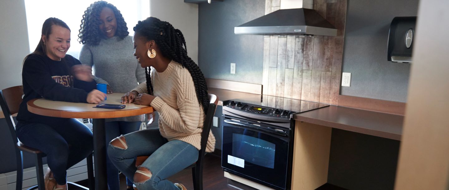 three female students having discussion in the kitchen