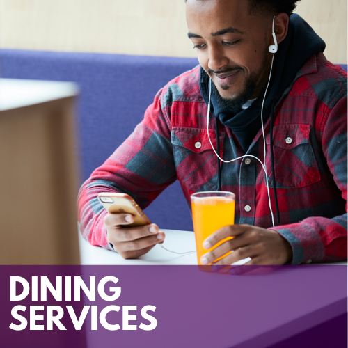 Male student sitting at a both in the University Dining Center with a beverage while looking at his phone