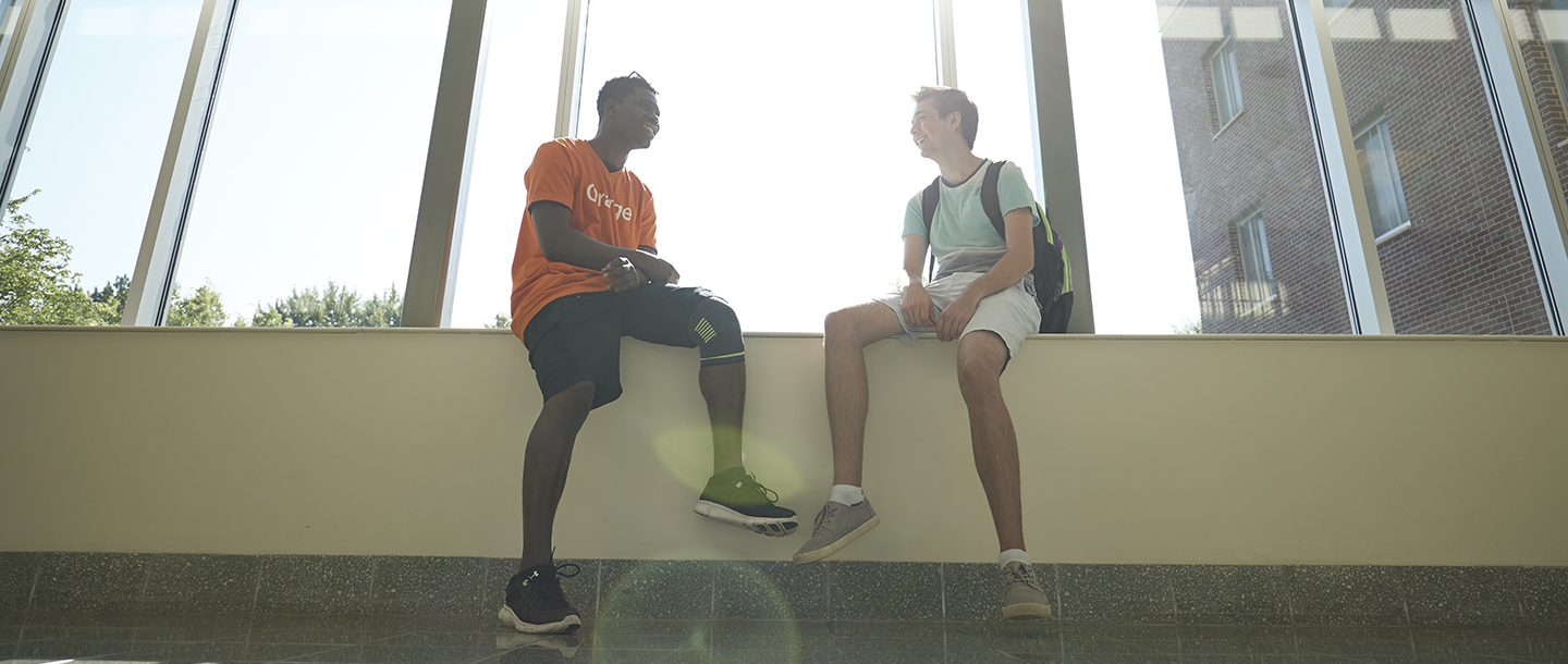 Two guys sitting near a big window and laughing