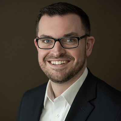 a person in a suit and glasses smiling